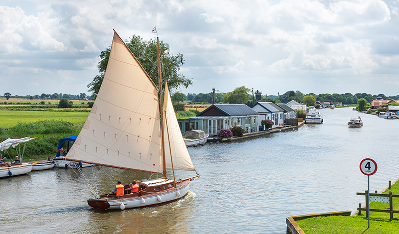 Photograph of wooden yacht sailing near Potter Heigham on the River Thurne, Norfolk Broads National Park