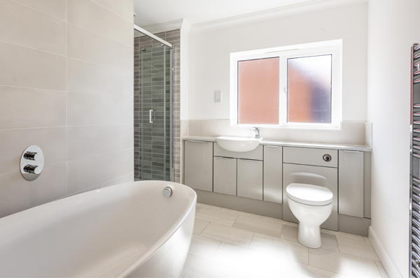 Badger Building Bathroom Photograph of bathroom with luxury oval bath, built in shower cubicle and fitted units with integrated sink and toilet