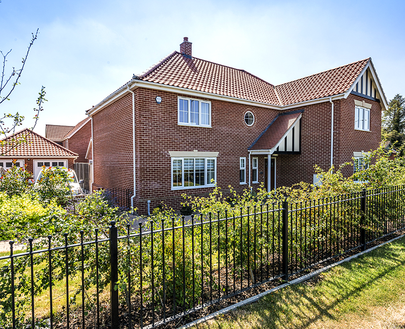 Badger Building new build house with well planted front garden and black metal railing fence